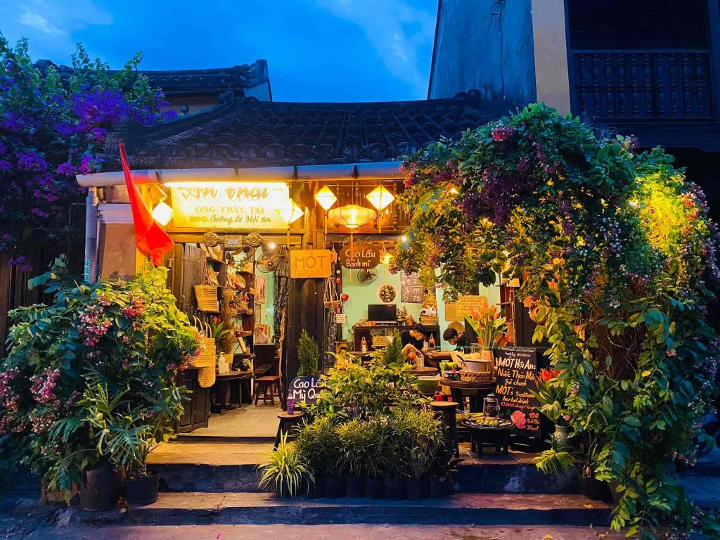 The peaceful and cozy interior of Mot Hoi An, featuring lush green plants and elegant lotus flower vases.