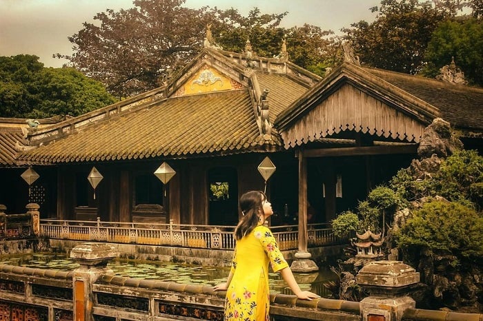 A visitor enjoying a cup of royal tea in the tranquil gardens of Dien Tho Palace in Hue.